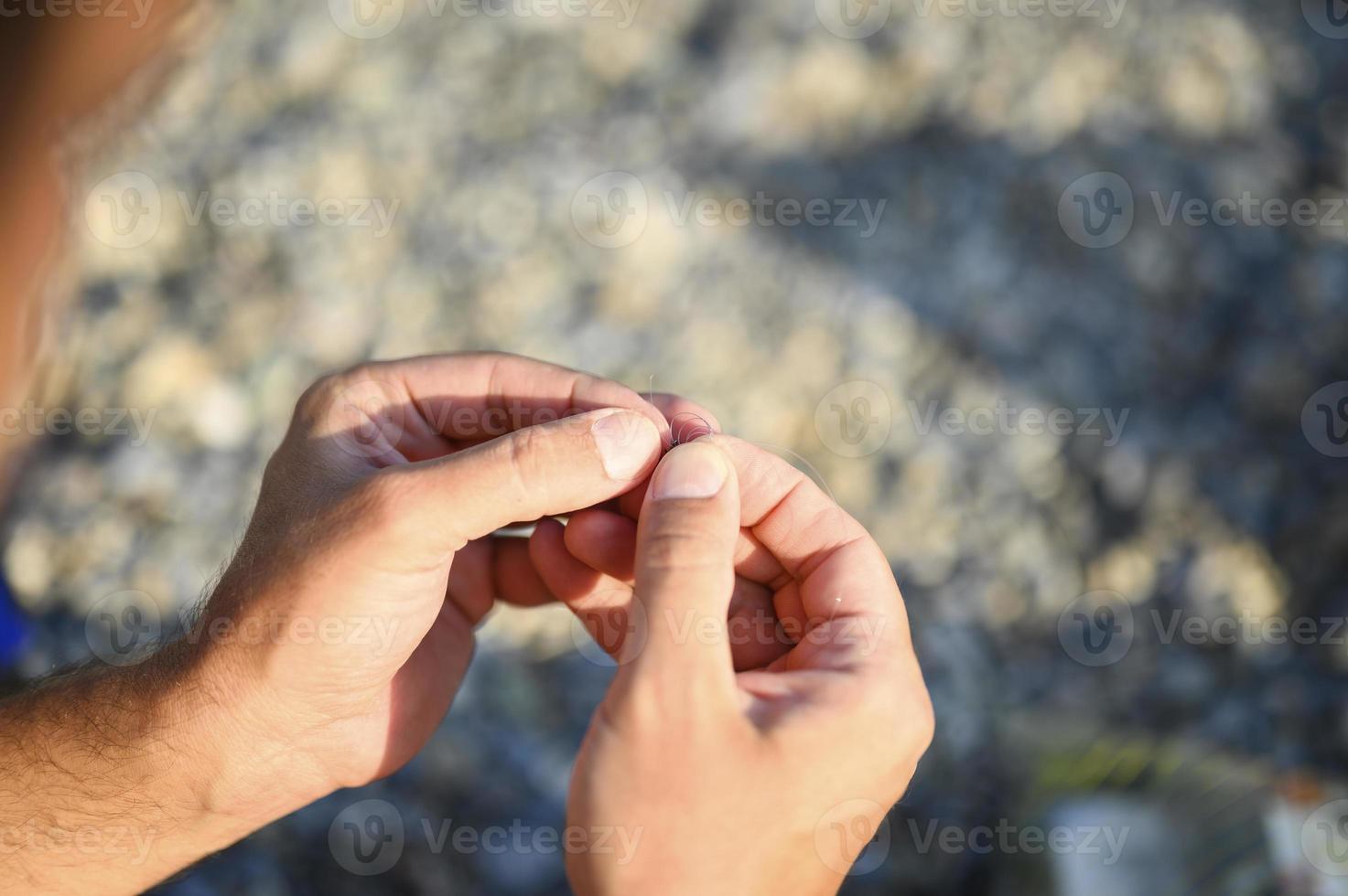 Las manos del hombre atando un hilo de pescar en un anzuelo de pesca foto