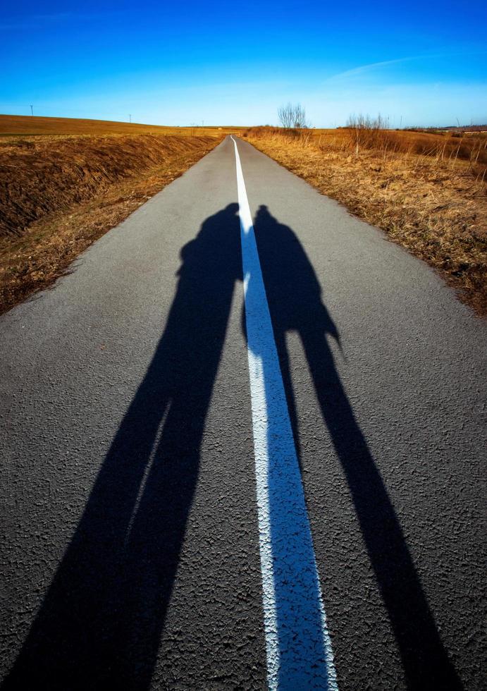 Long shadows of people on the road photo