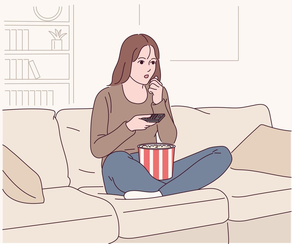 una mujer está sentada en el sofá comiendo palomitas de maíz y viendo una película. vector