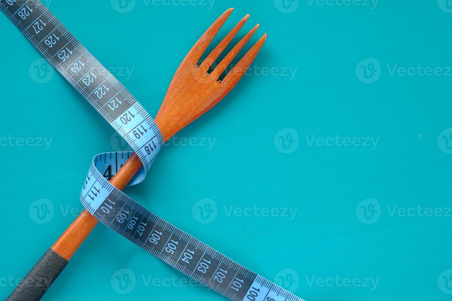 Fork with measurement tape on blue background photo