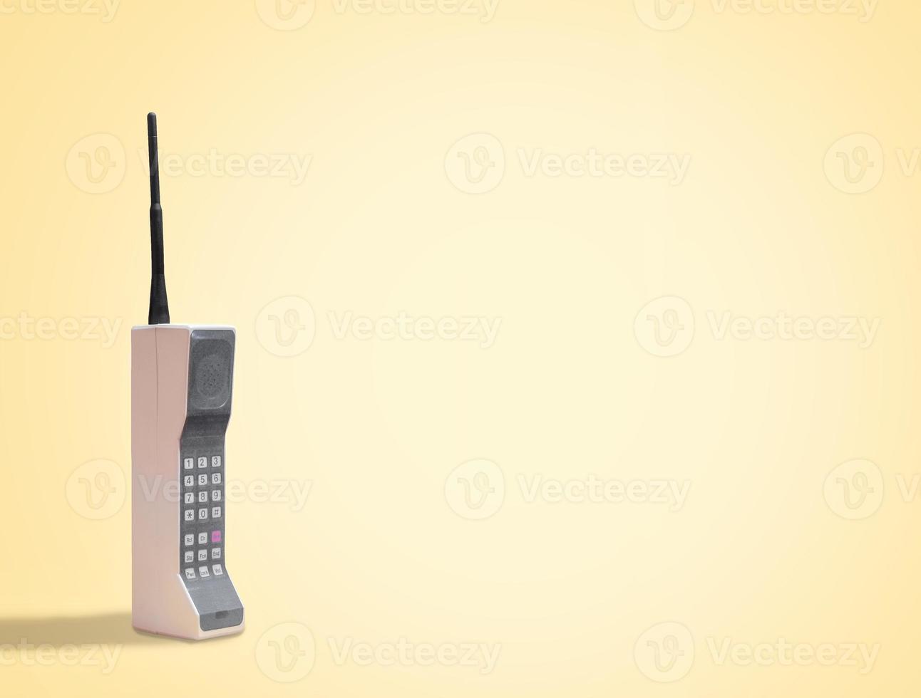 Vintage 80's mobile phone on yellow retro background with space for copy and text photo