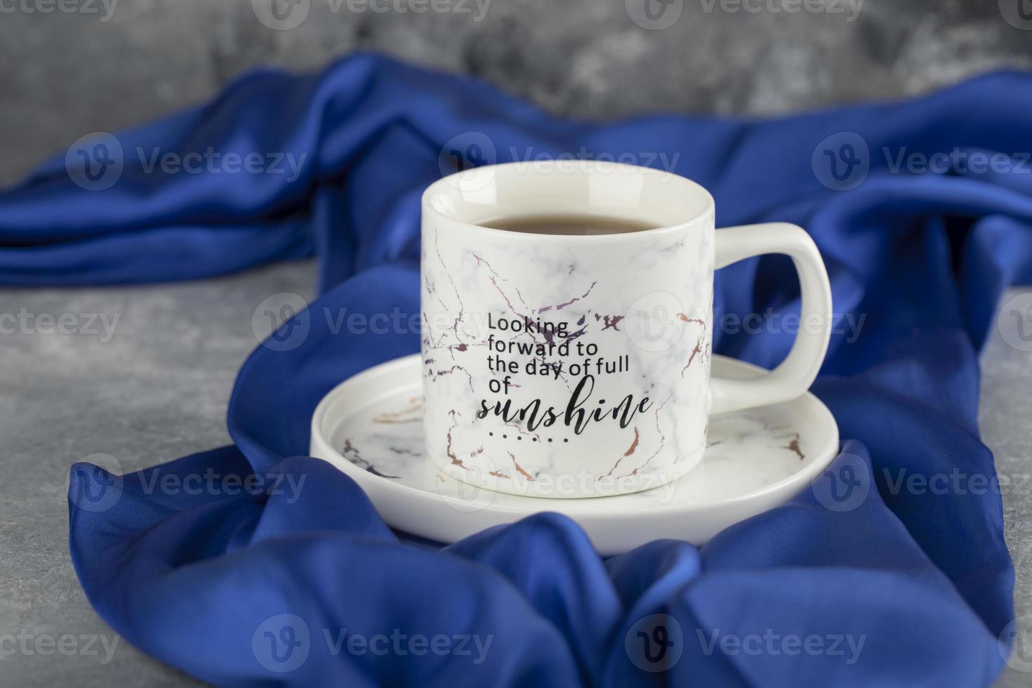 A white ceramic cup on a blue tablecloth photo