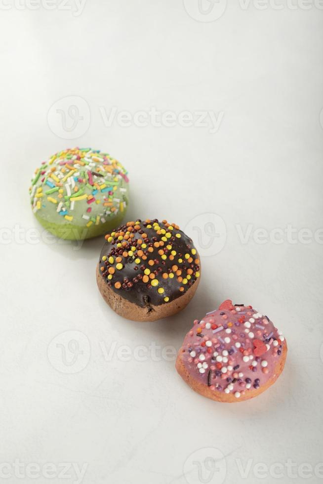 Rosquillas pequeñas dulces de colores sobre un fondo blanco. foto