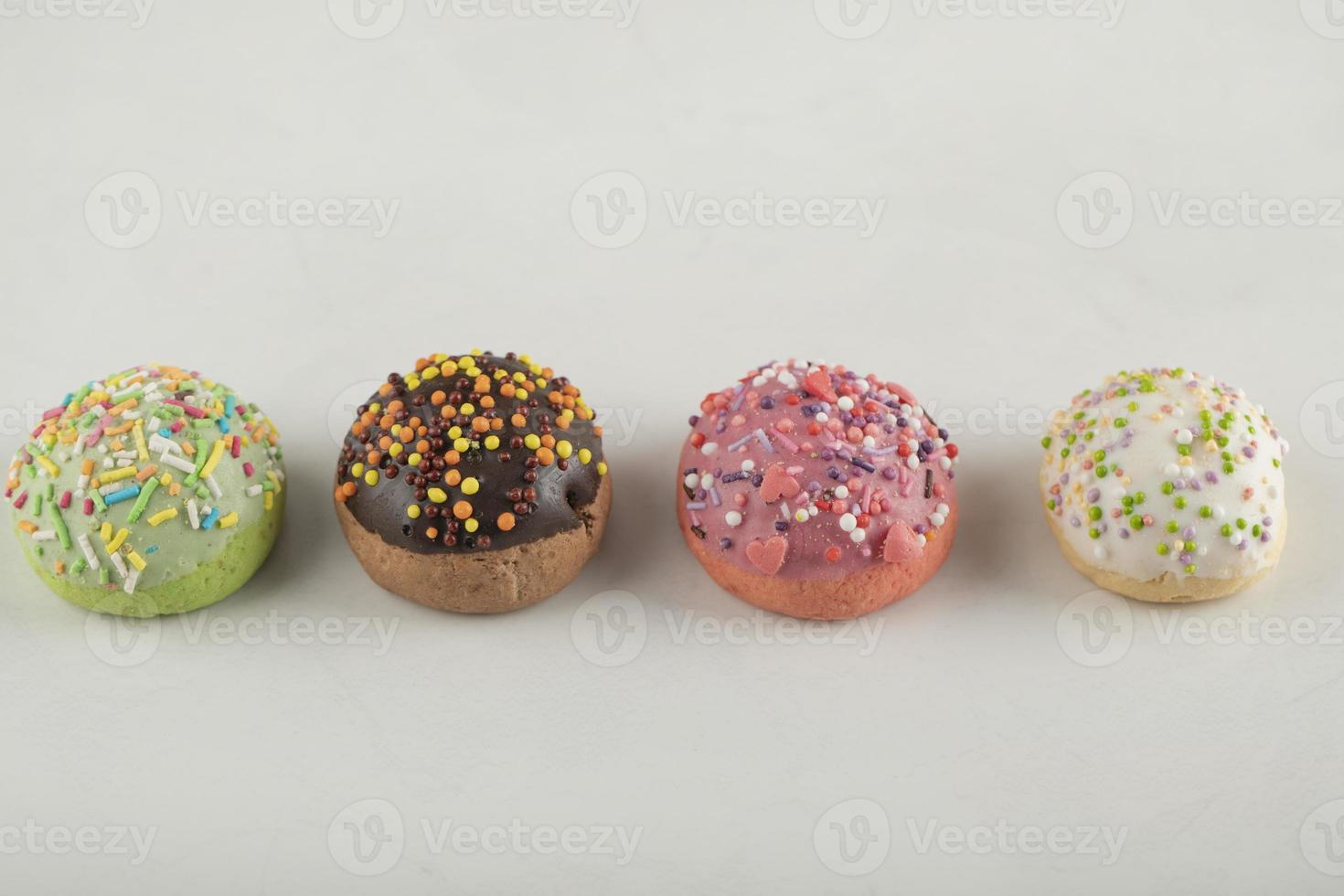 Rosquillas pequeñas dulces de colores sobre un fondo blanco. foto