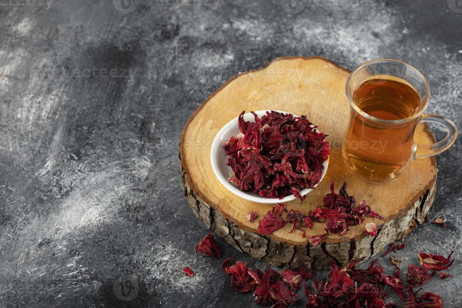 una taza de té caliente con flores rojas secas en una pieza de madera foto