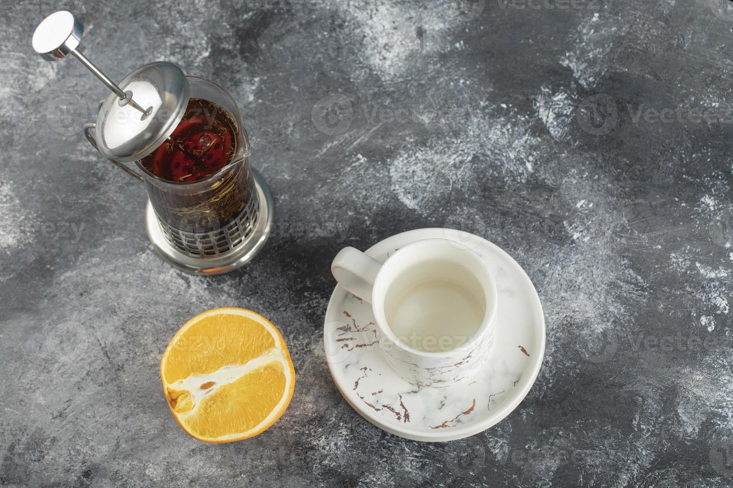 A white ceramic cup of drink with a teapot on a marble background photo