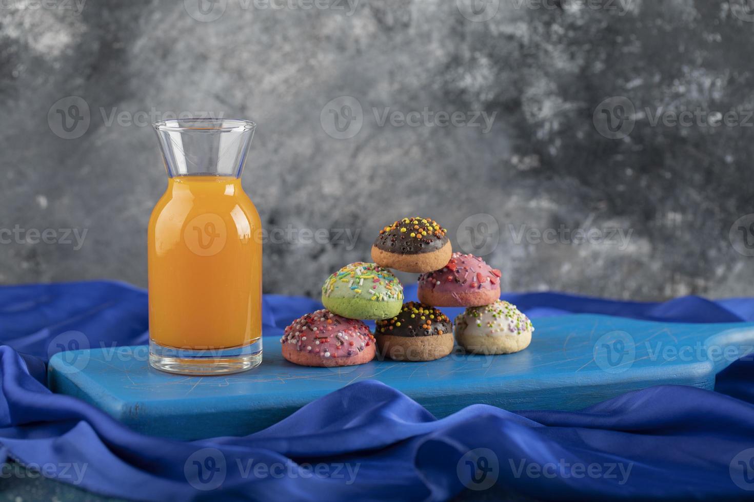 A glass bottle of juice with colorful doughnuts photo