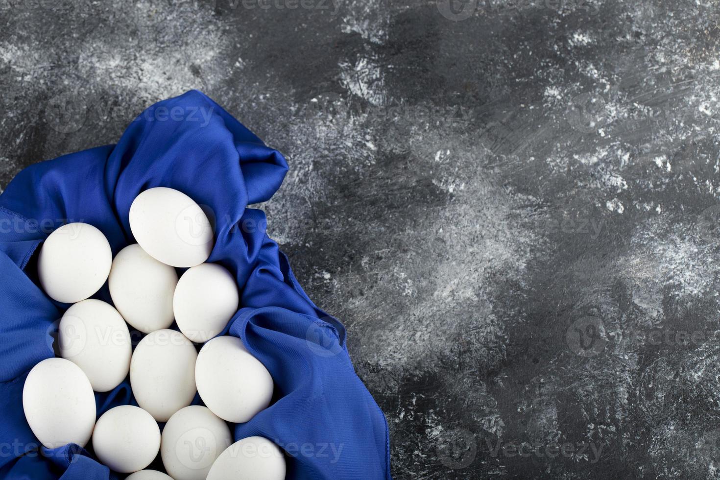 Huevos de gallina cruda blanca con sobre un mantel azul foto