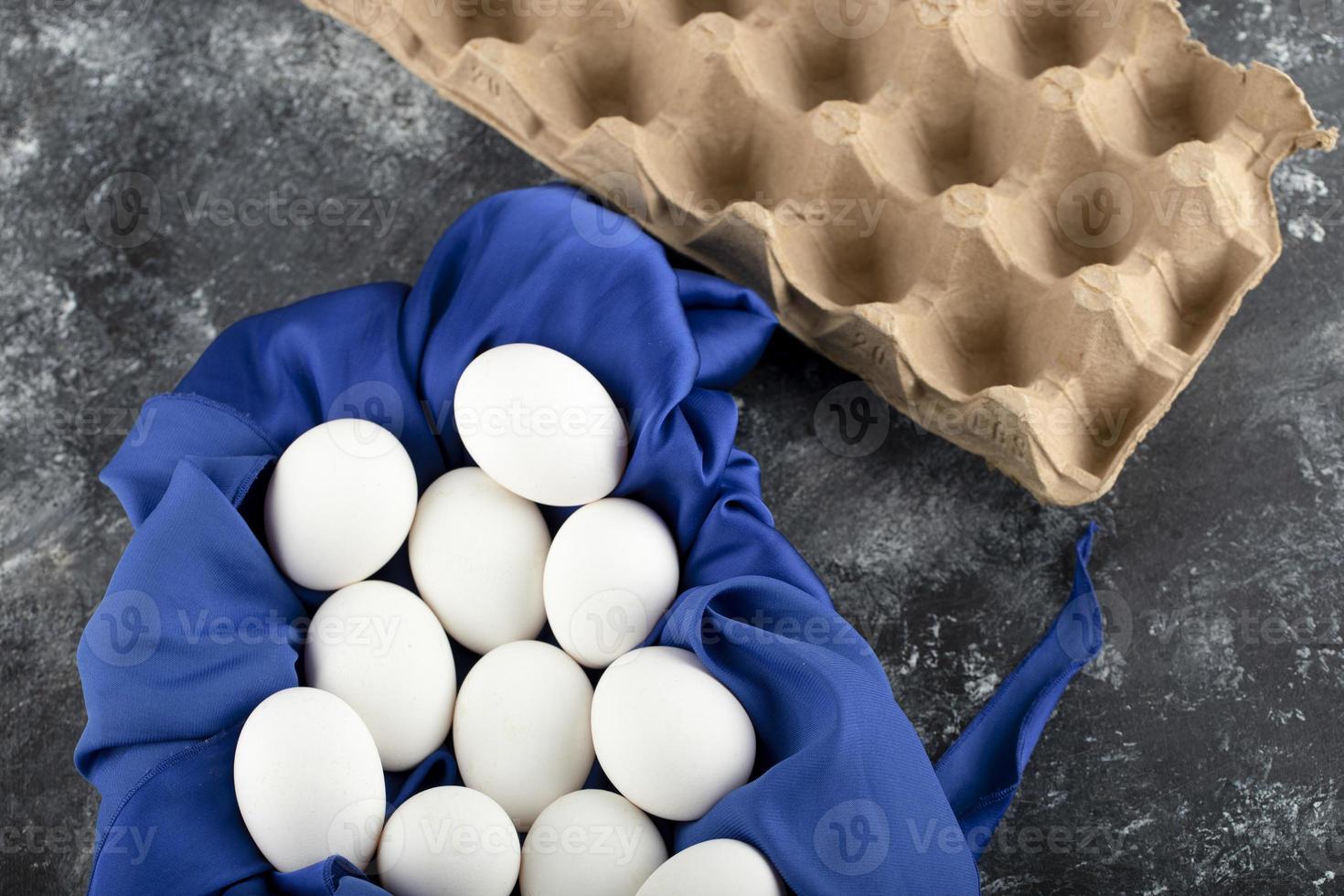 White raw chicken eggs with on a blue tablecloth photo