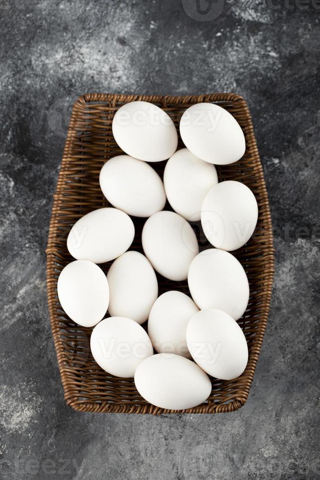 A wooden wicker full of white raw chicken eggs photo