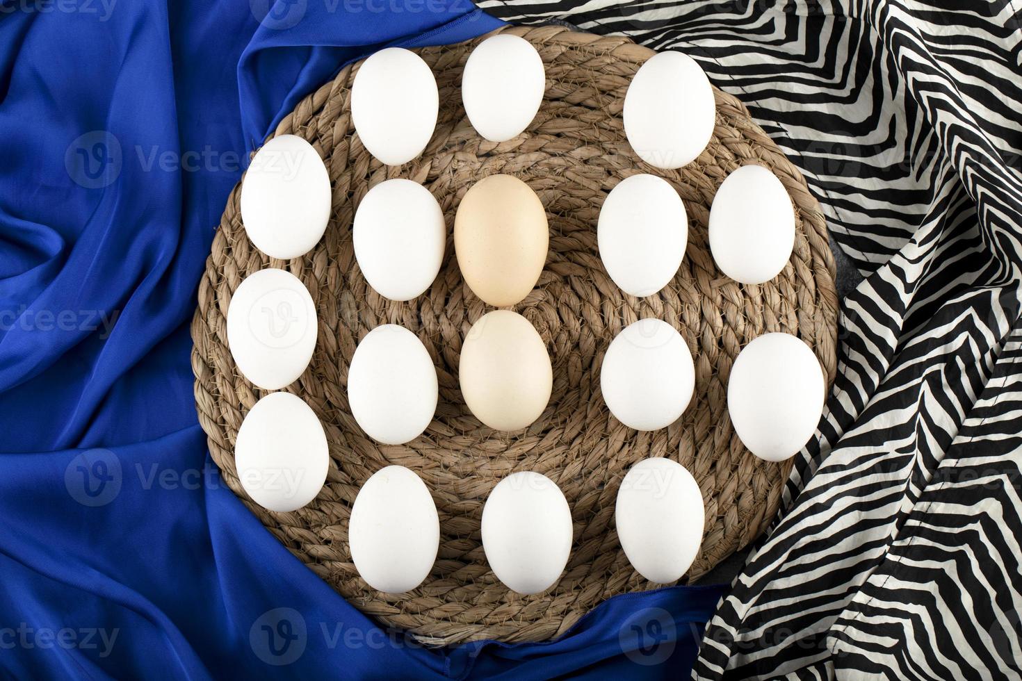 Brown and white raw chicken eggs on a wooden piece on blue cloth photo