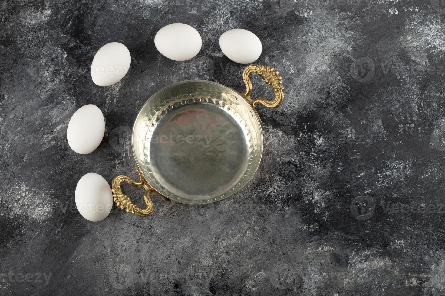 White raw chicken eggs with a saucepan photo