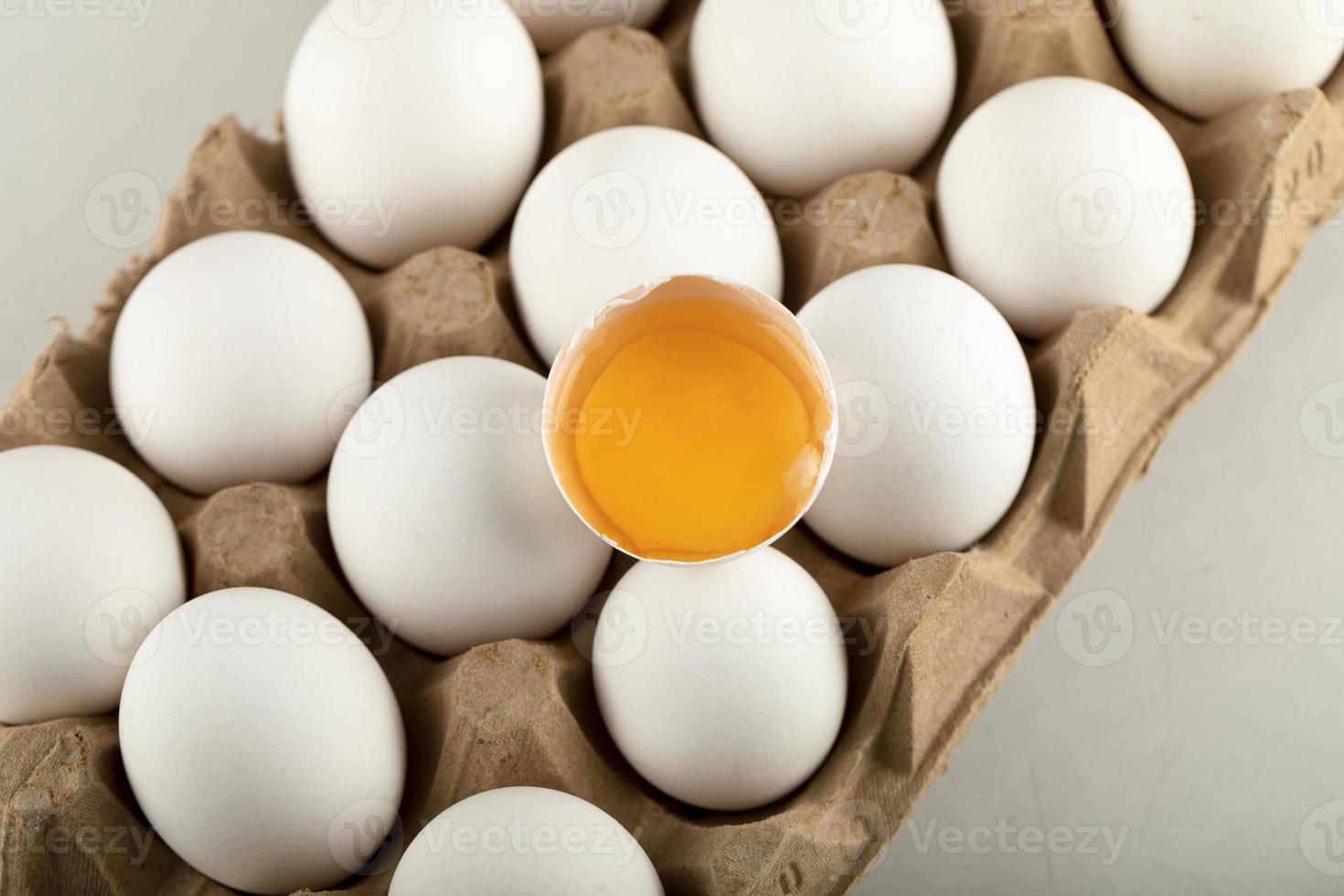 Huevos de gallina cruda en una caja de huevos sobre un fondo blanco. foto