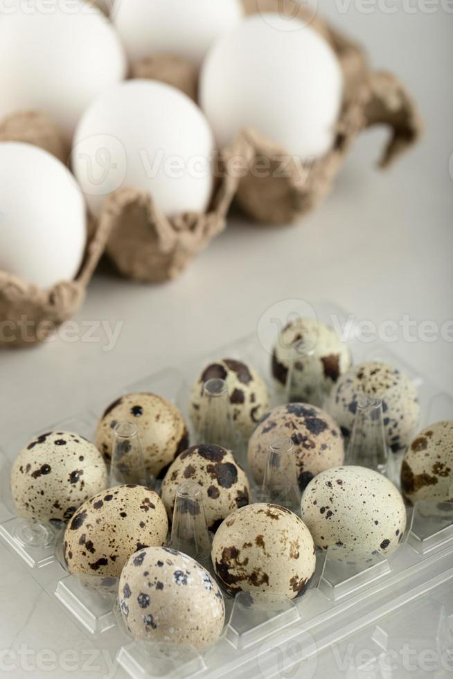 huevos de gallina crudos en un recipiente de cartón y huevos de codorniz foto