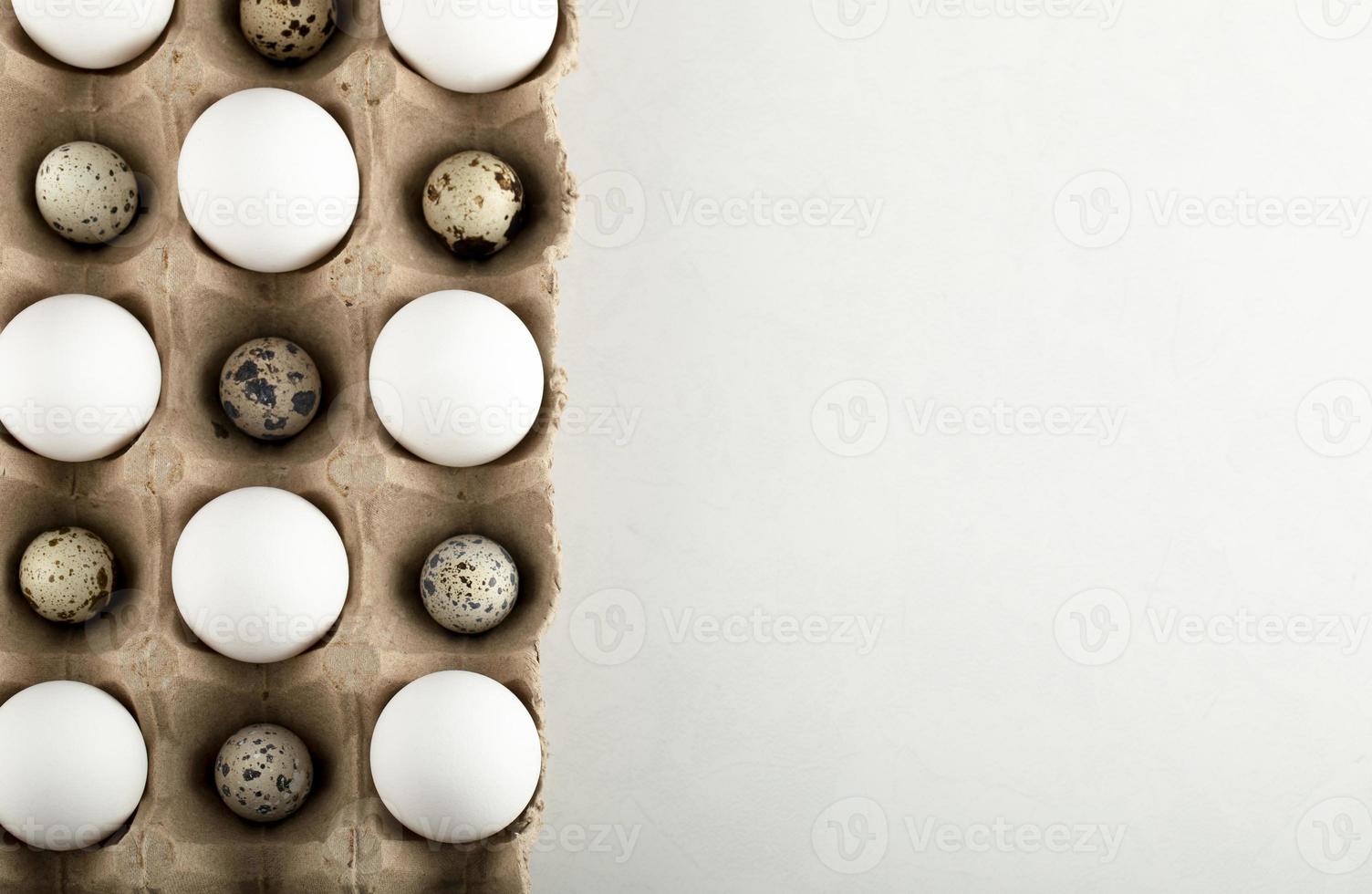 huevos de codorniz y pollo crudo en un recipiente de cartón foto