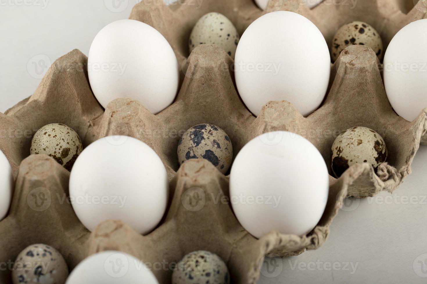 huevos de codorniz y pollo crudo en un recipiente de cartón foto