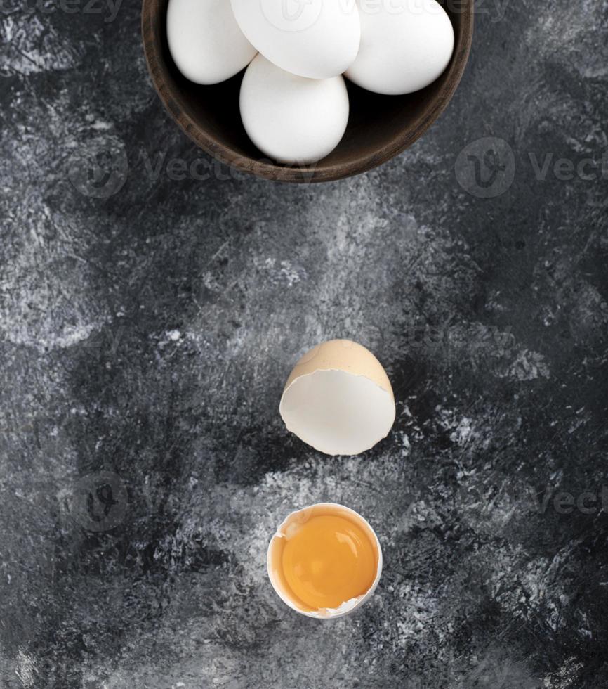 Bowl of white eggs and yolk on a marble background photo
