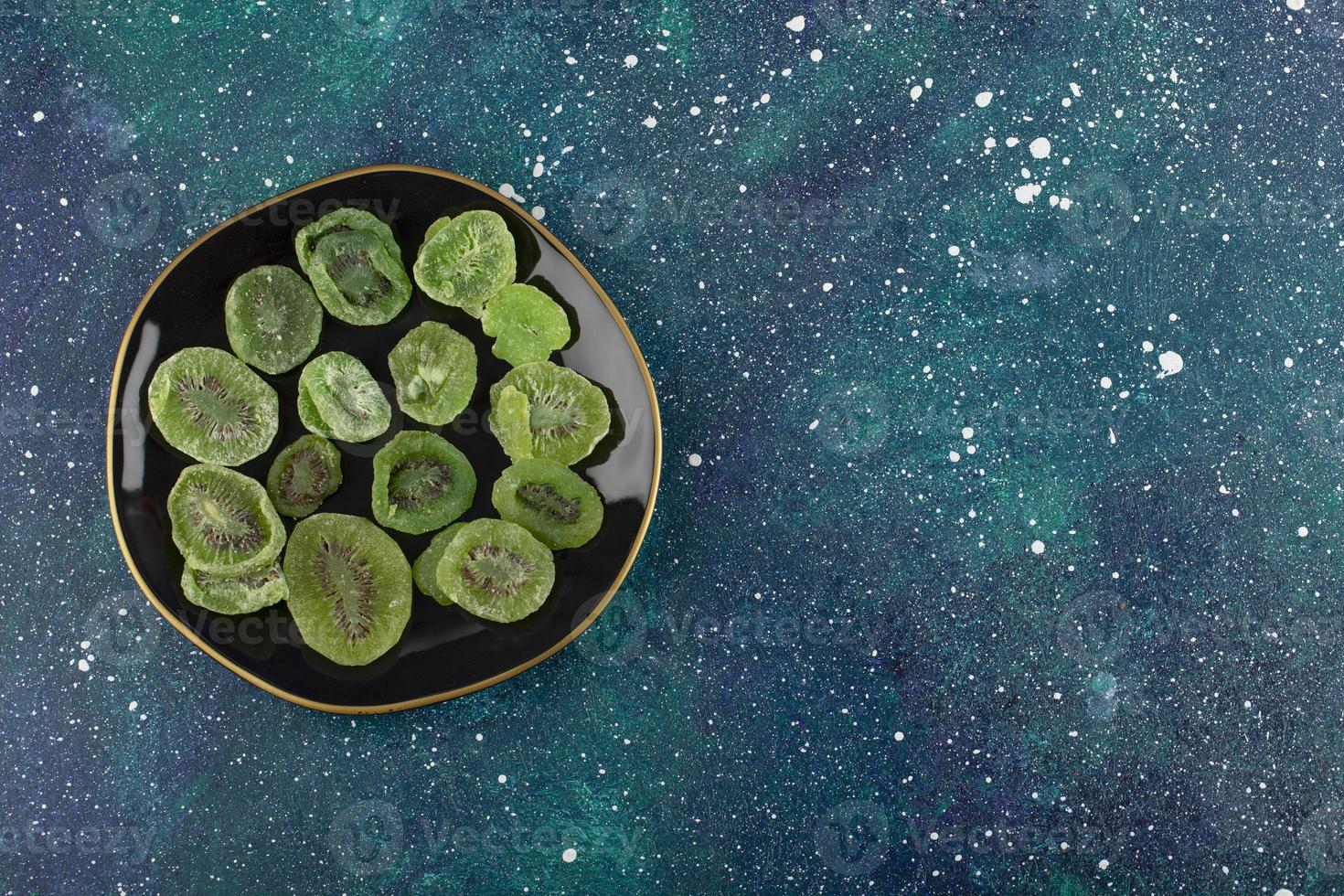 Dried slices of kiwi on a black plate photo