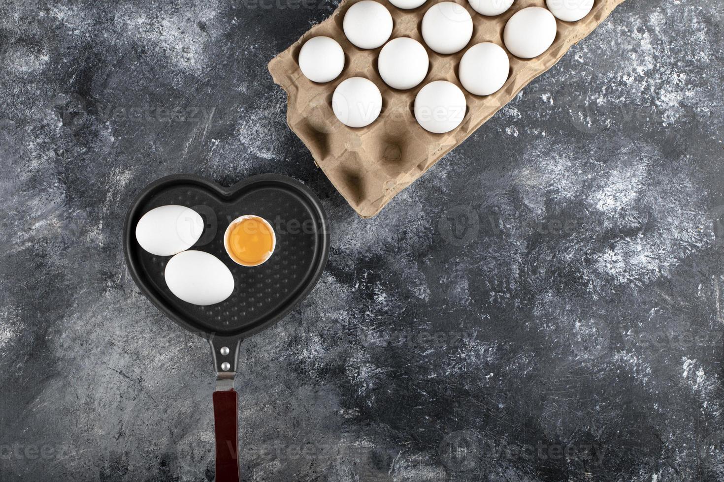 Pan and container of eggs on a marble background photo