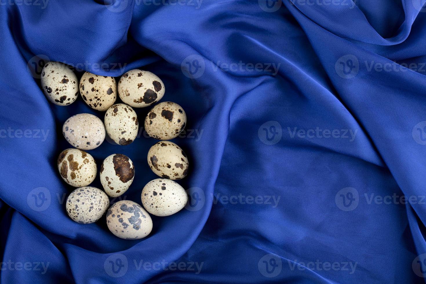 Huevos de codorniz de granja frescos sobre un paño de satén azul foto