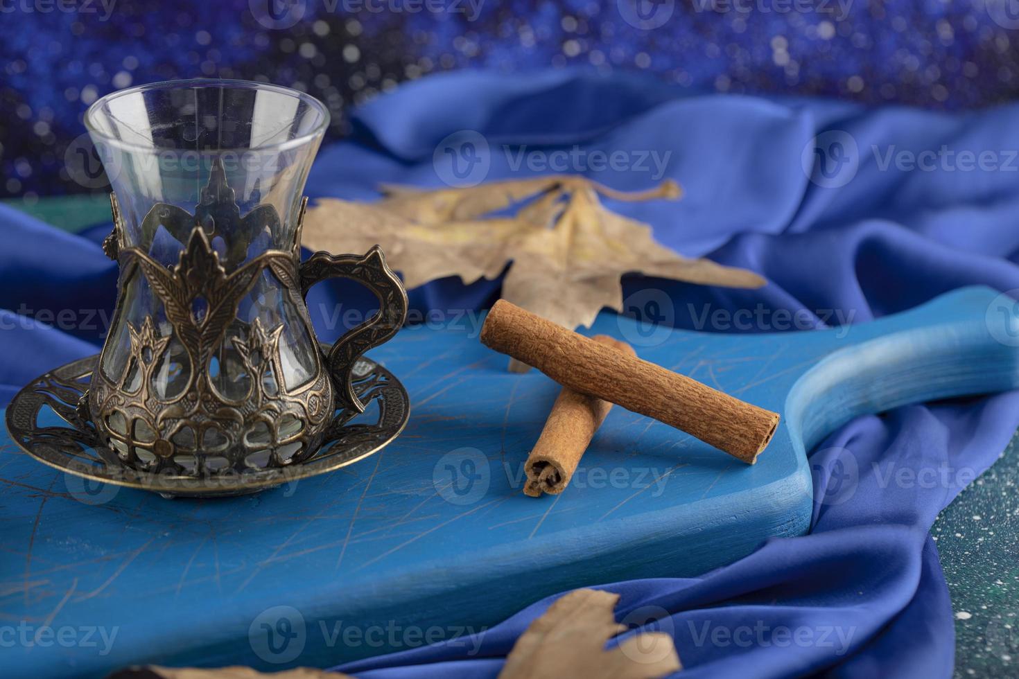 Empty glass and cinnamon sticks on a blue board photo