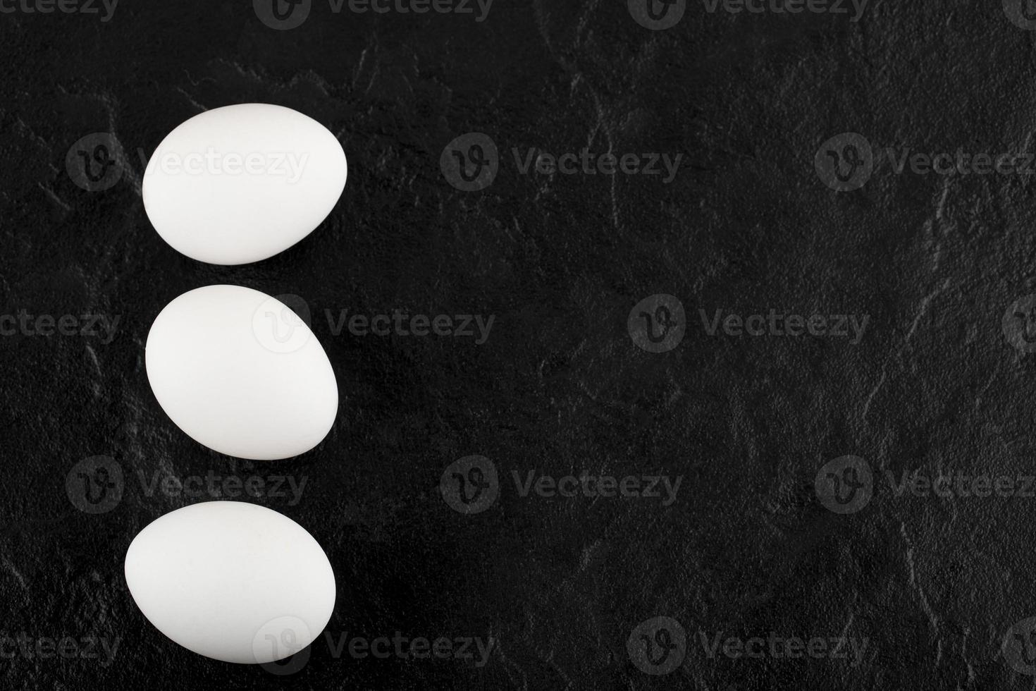 Three white eggs on a black background photo
