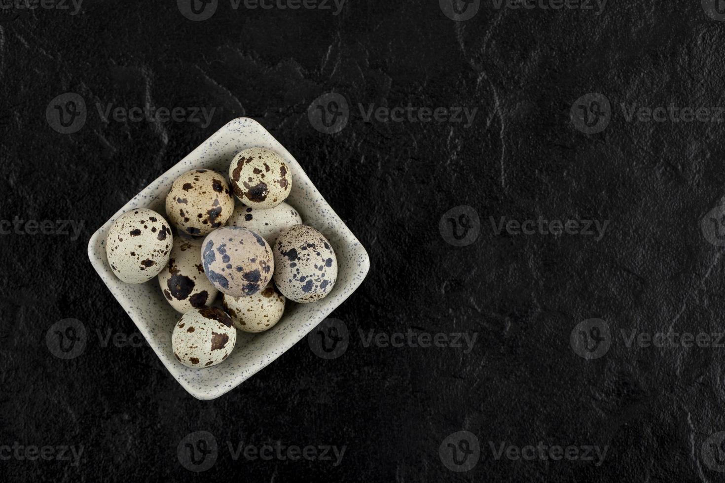 Bowl of quail eggs on a black background photo