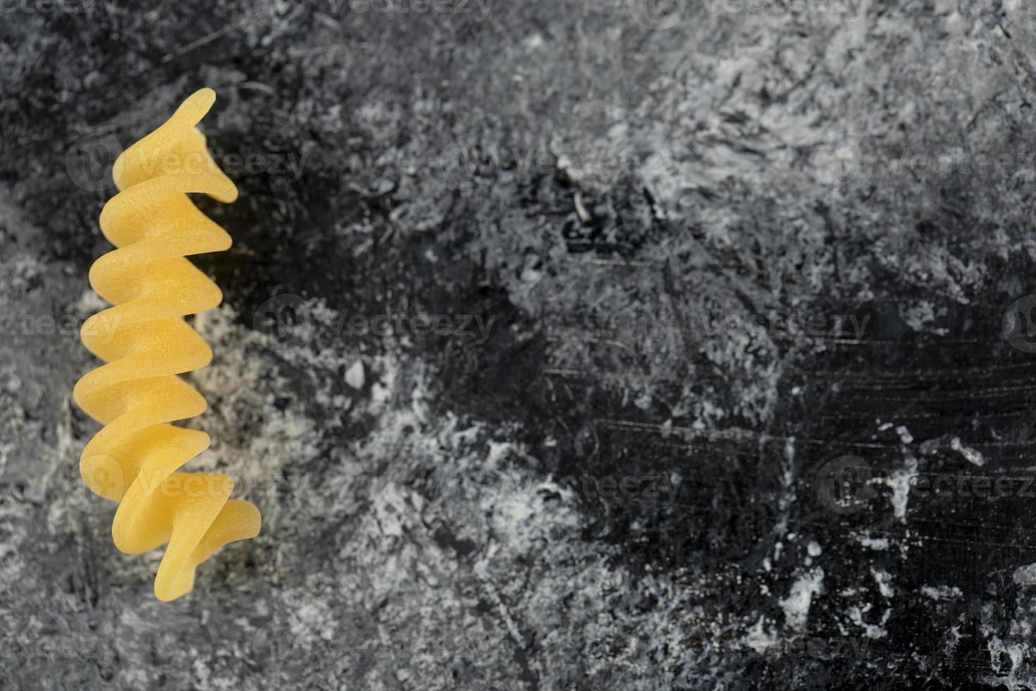 Single raw fusilli pasta on a marble background photo