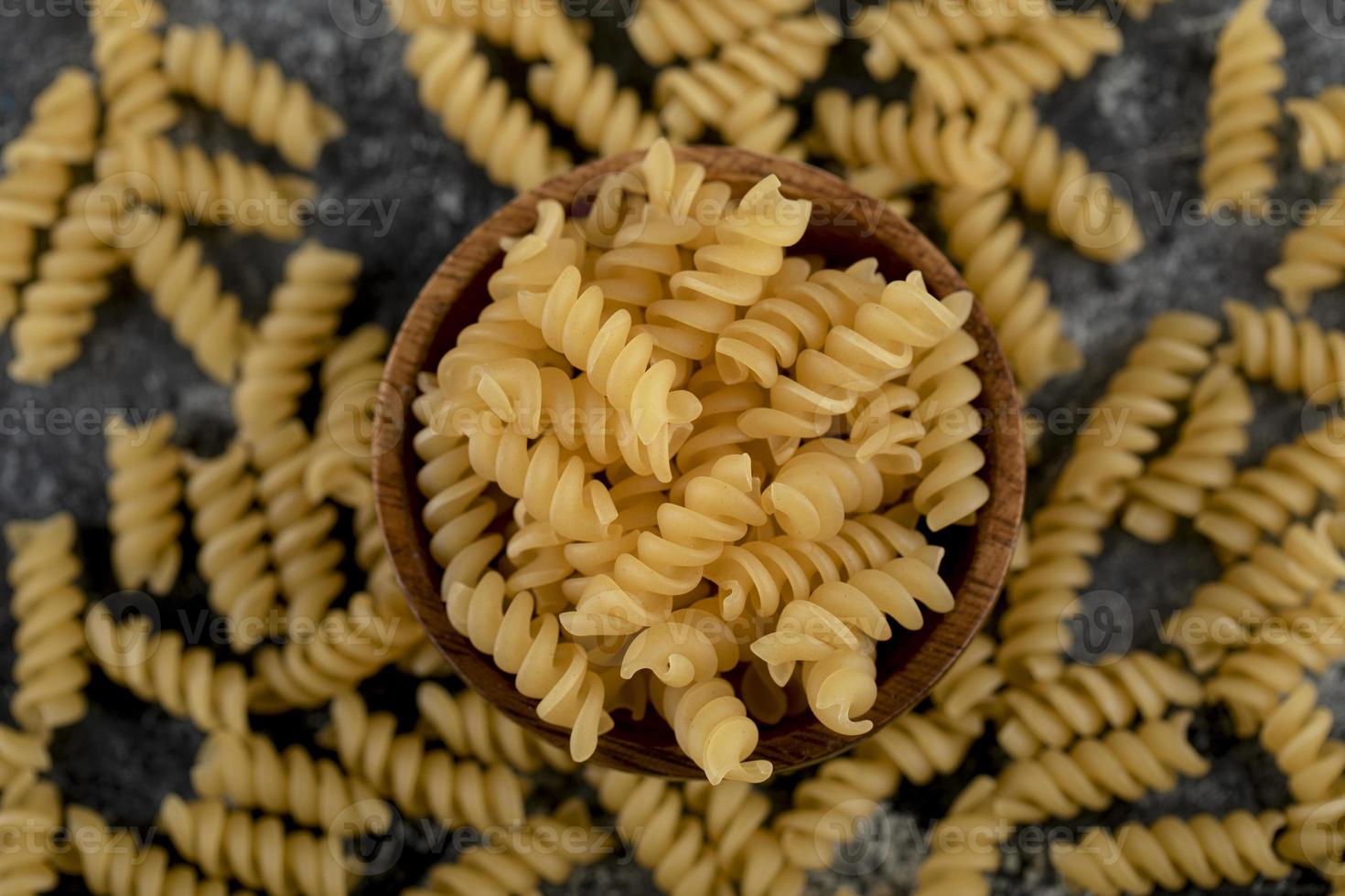 Bowl of raw fusilli pasta on a marble background photo