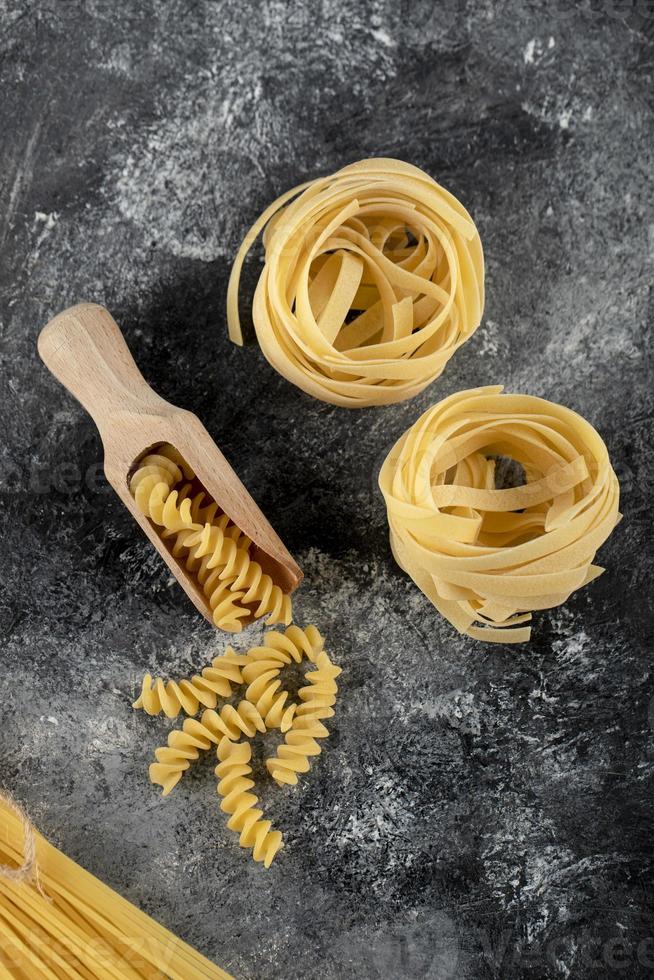 Nidos de tallarines y fusilli sobre un fondo de mármol foto