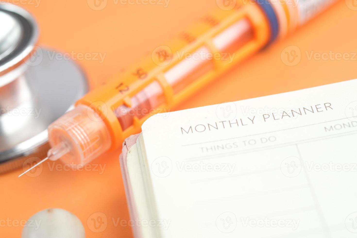 pluma de insulina y planificador semanal en la mesa foto