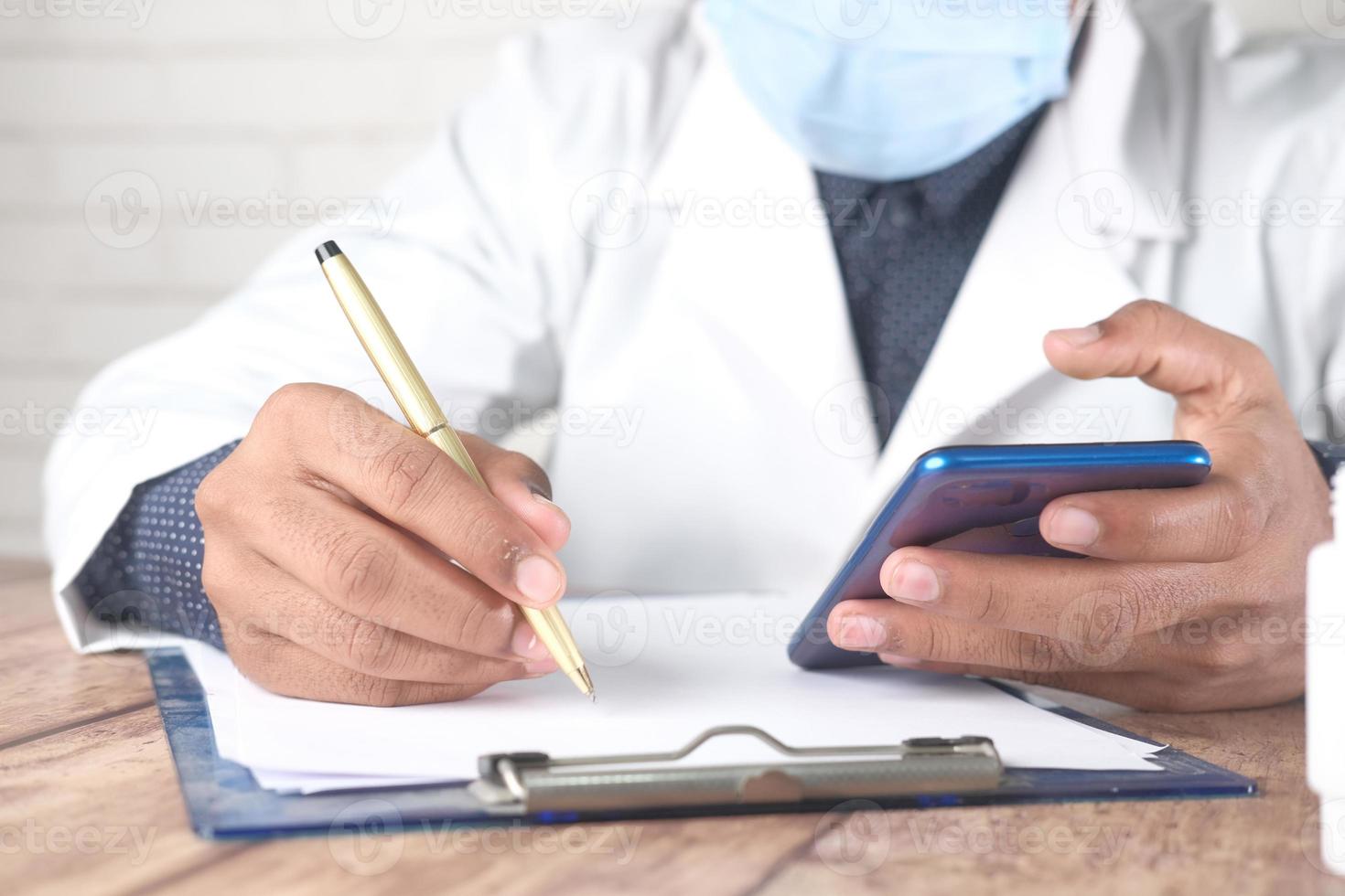 médico escribiendo prescripción en el escritorio foto