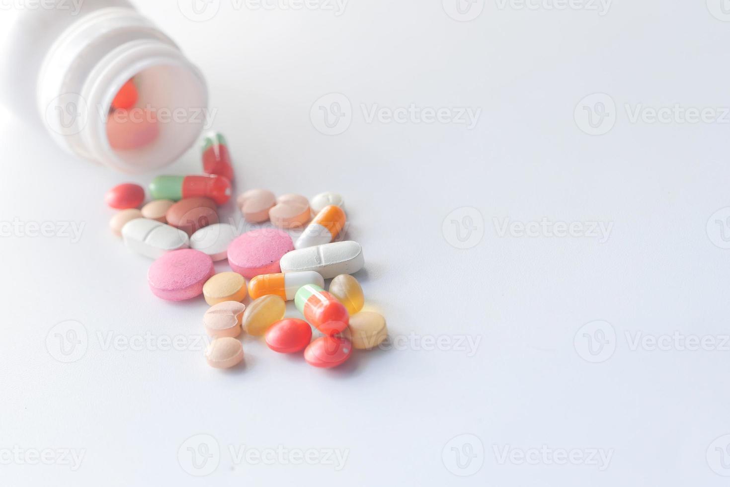 Close up of colorful pills spilling on white background photo