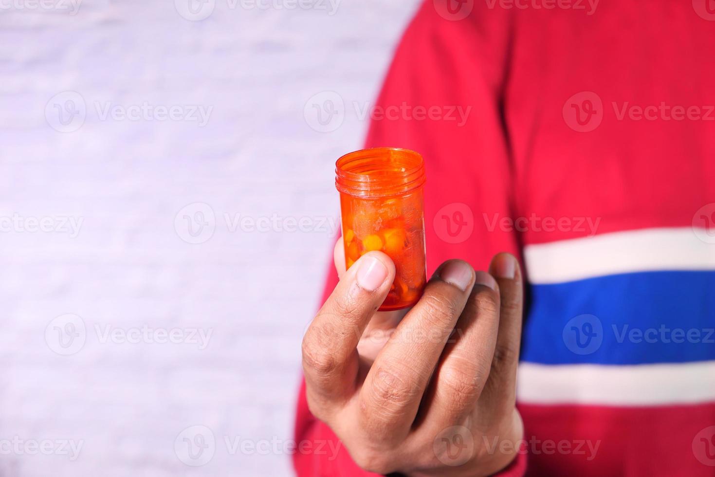 La mano de la persona que sostiene el envase de la píldora aislado en blanco foto