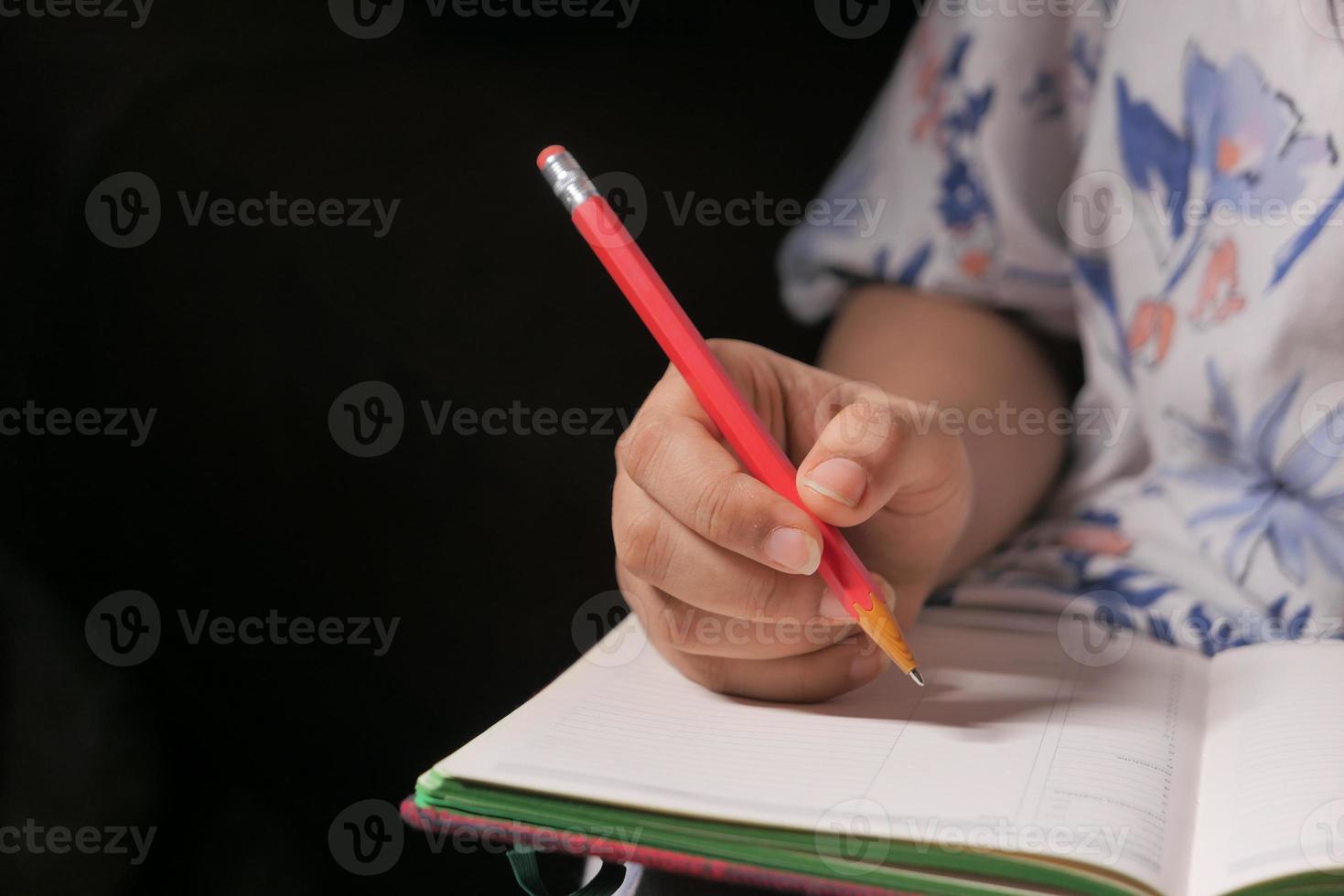 Cerca de la mano de mujer escribiendo en el bloc de notas foto