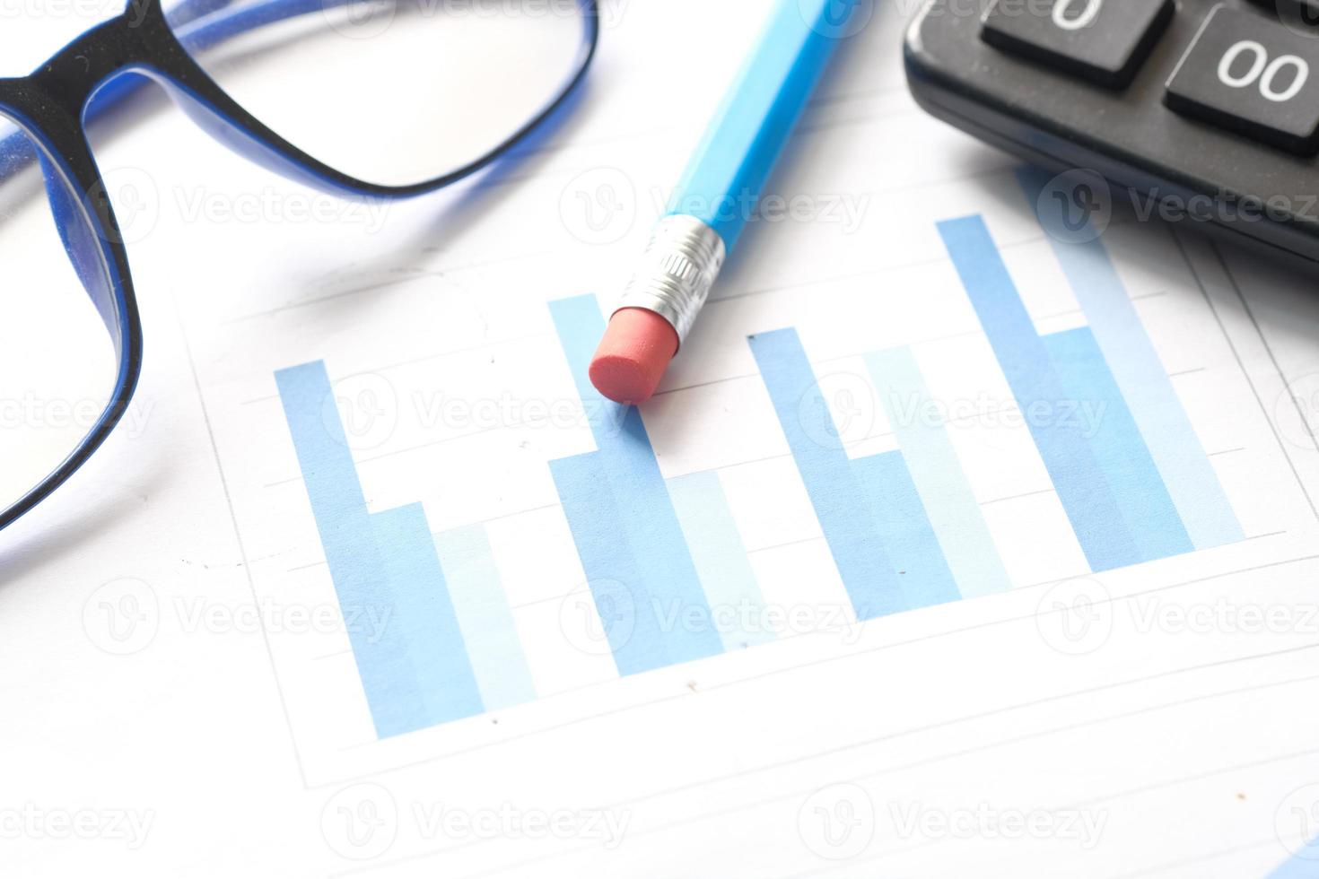 gráfico financiero, calculadora y bloc de notas en la mesa foto