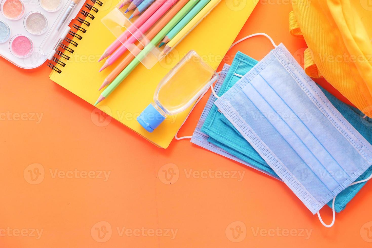 Colorful school supplies on orange background photo