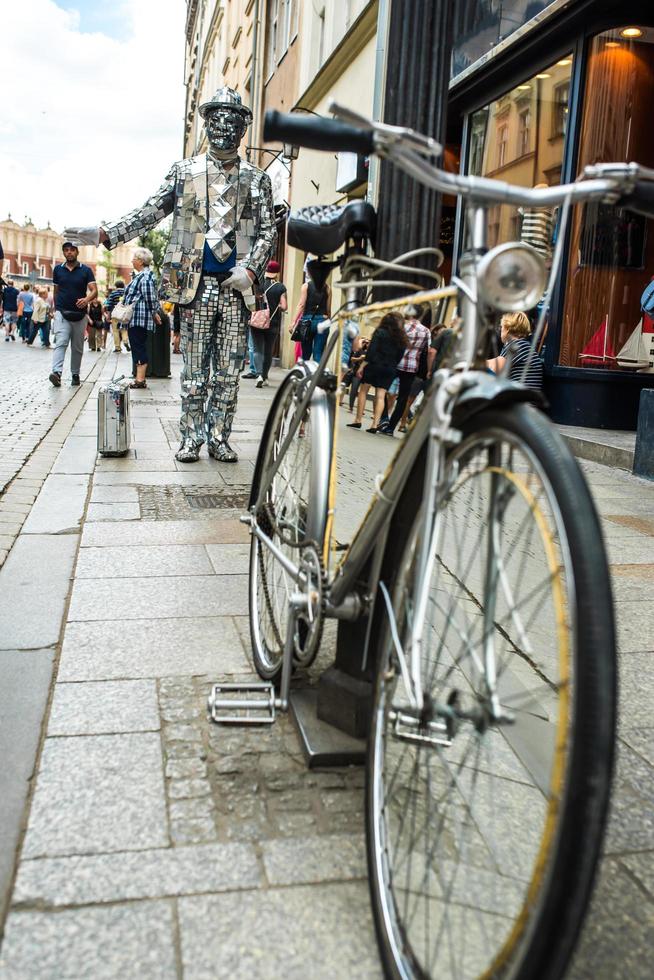 Cracovia, Polonia 2017- un hombre con un traje de espejo con una maleta y una bicicleta foto