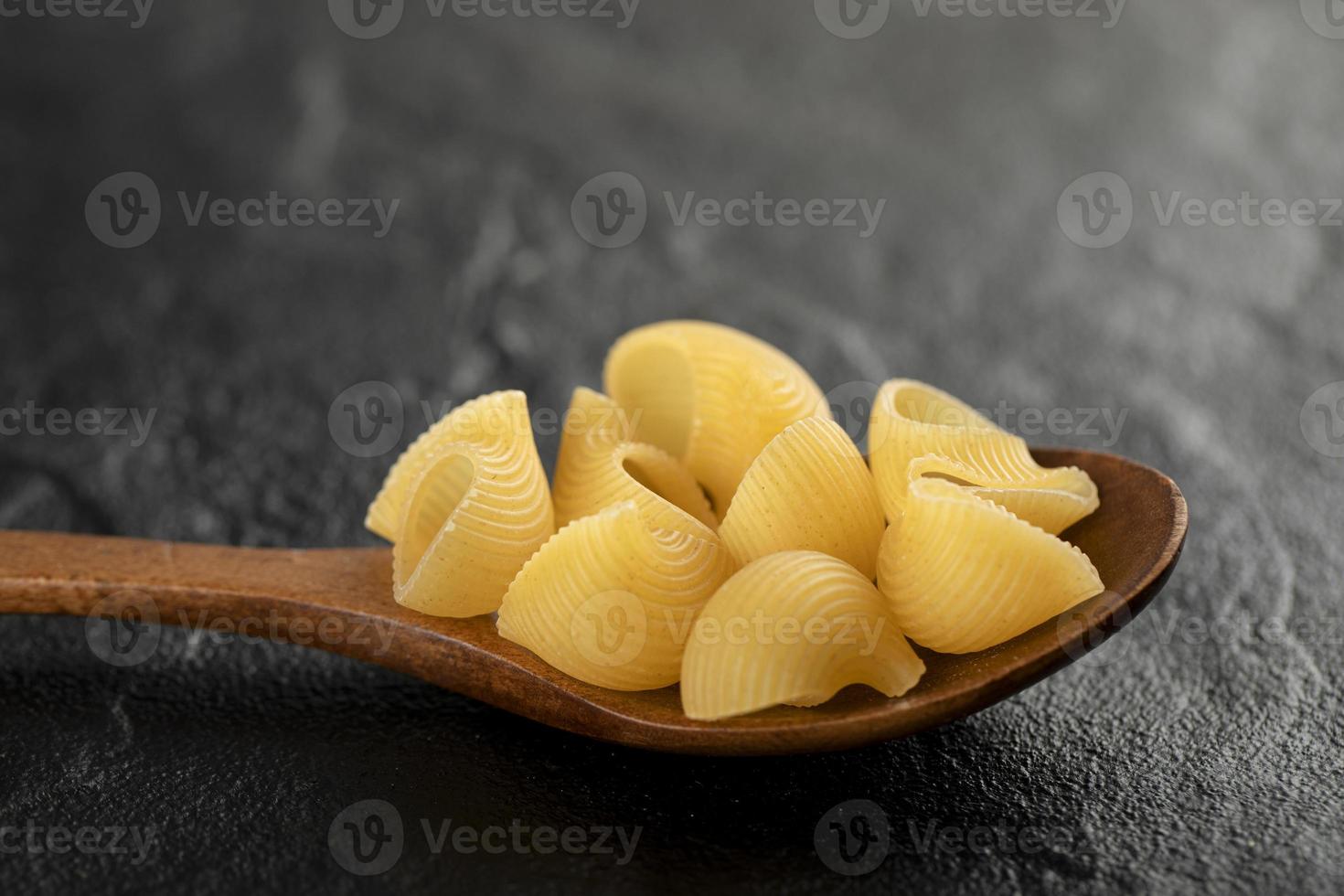 A wooden spoon of uncooked conchiglie macaroni photo