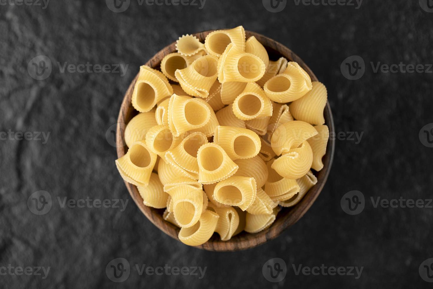 Italian uncooked pasta conchiglie in a wooden bowl photo