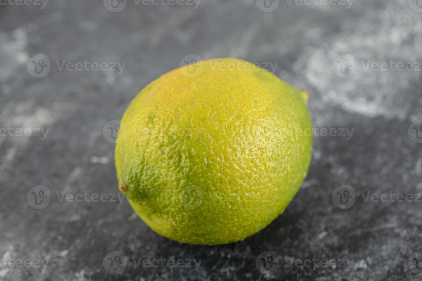 A green ripe lemon on a marble background photo