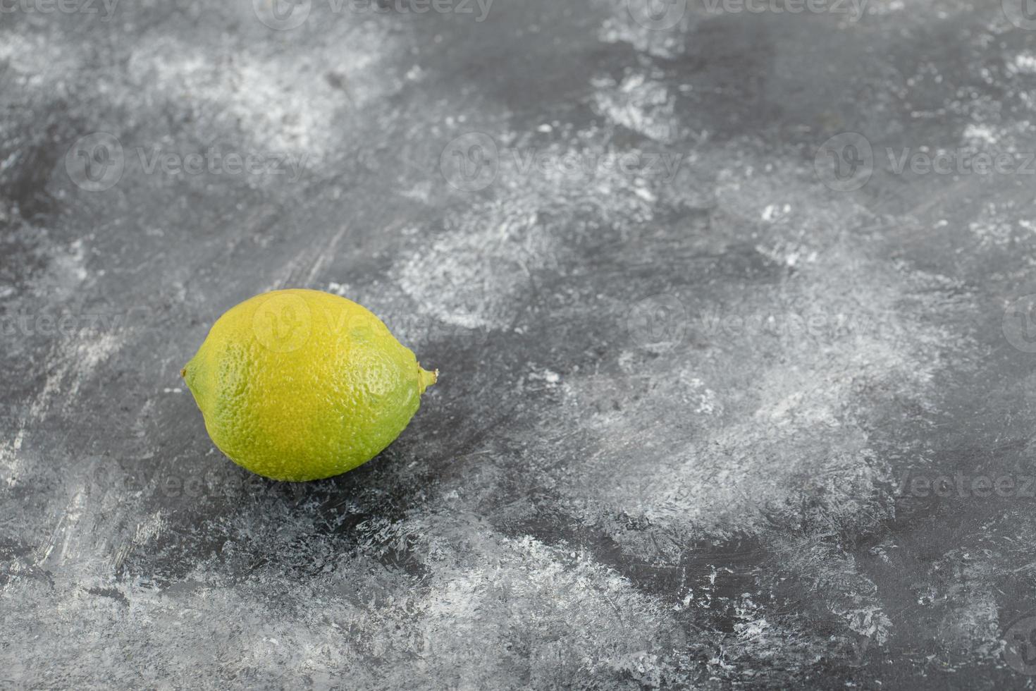 A green ripe lemon on a marble background photo