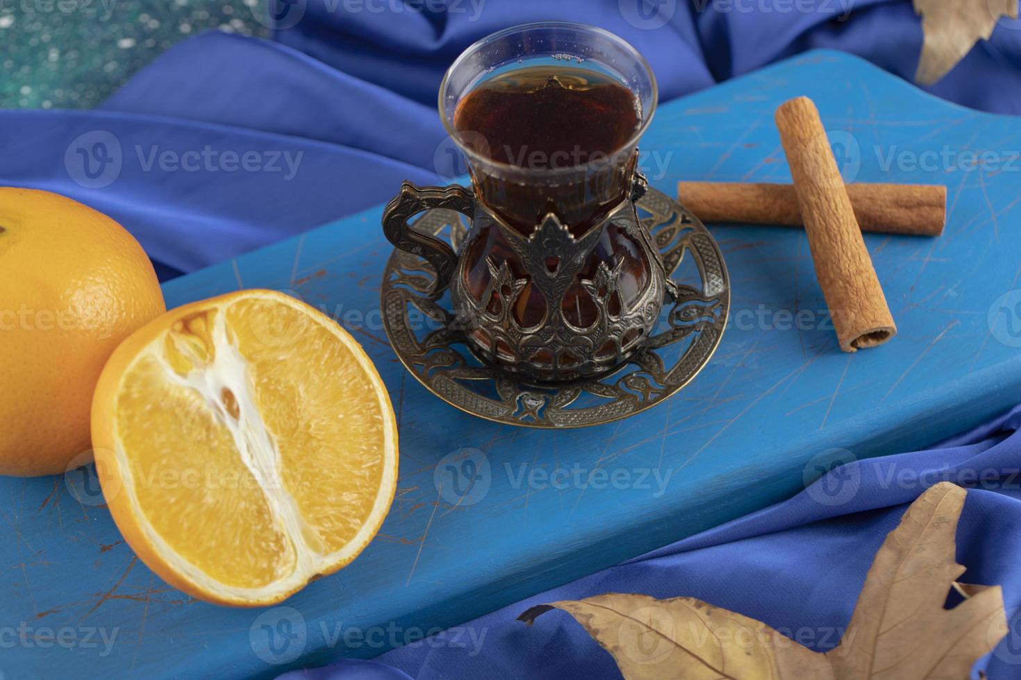 un té de vidrio con ramas de canela en una tabla de cortar de madera foto