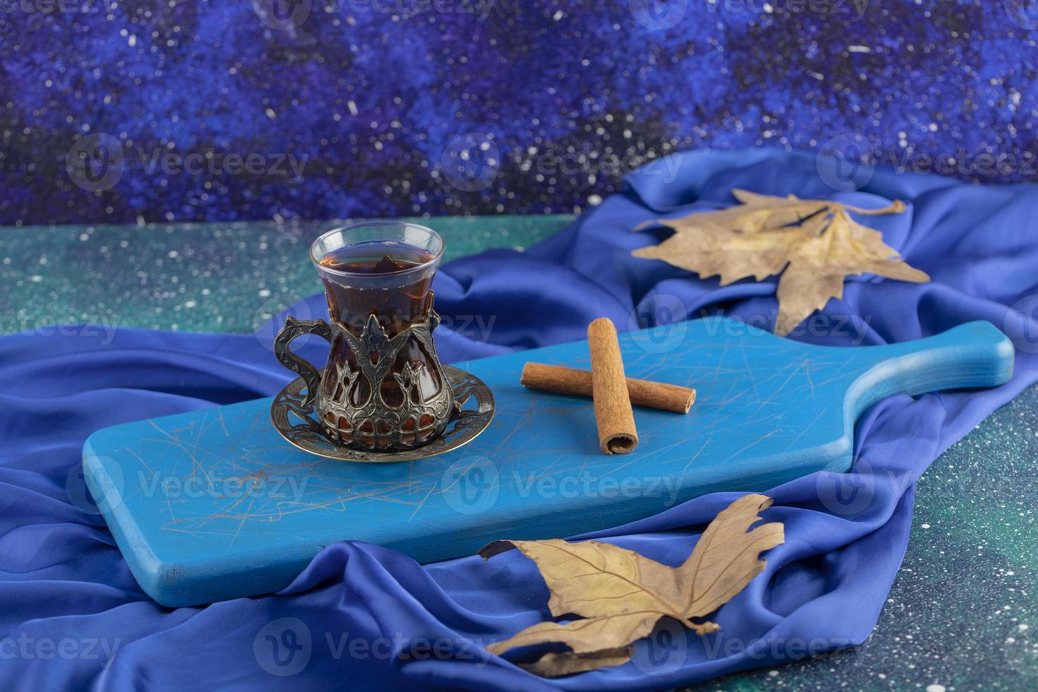 A glass tea with cinnamon sticks on a wooden cutting board photo