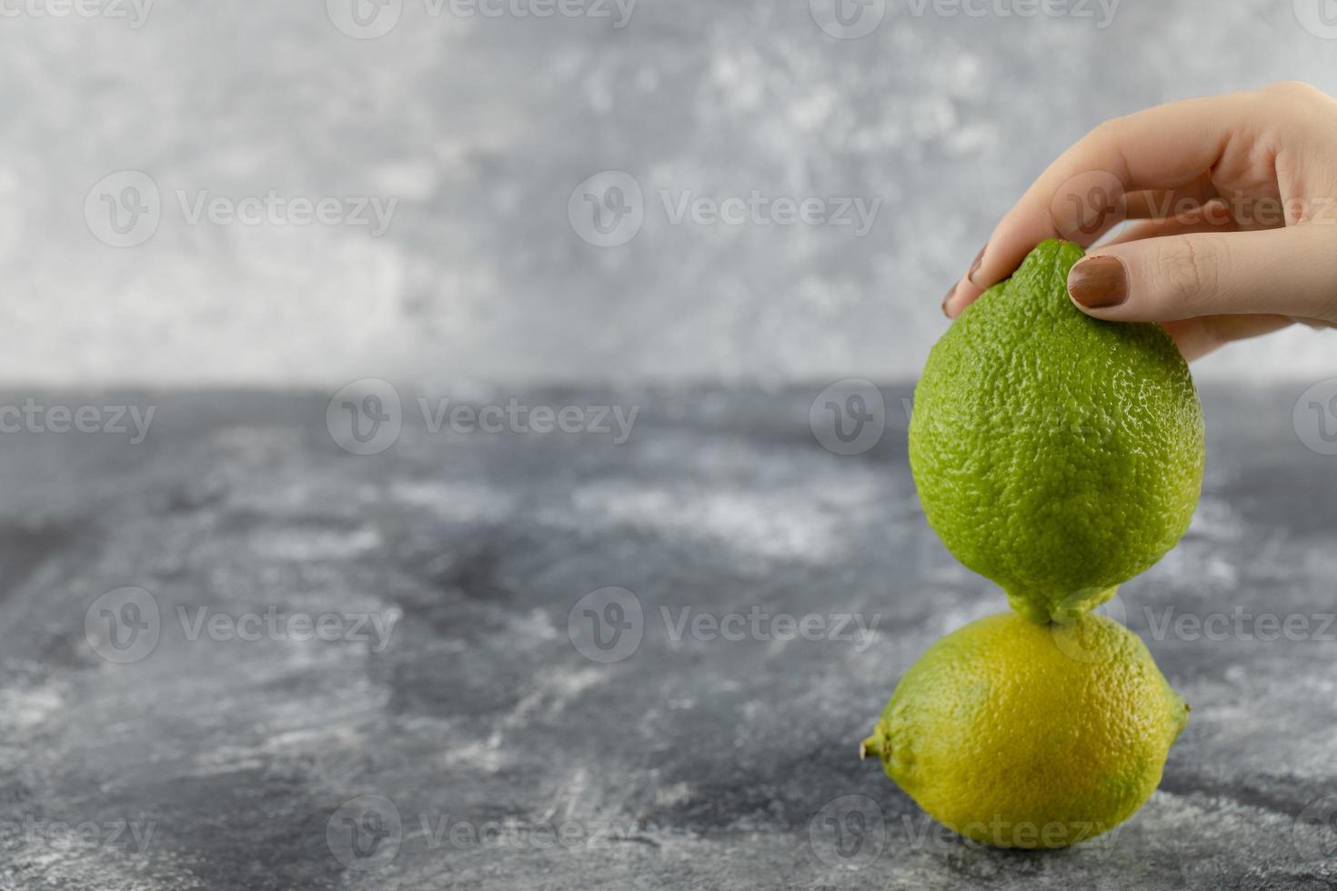 Woman hand holding two green fresh lemons photo