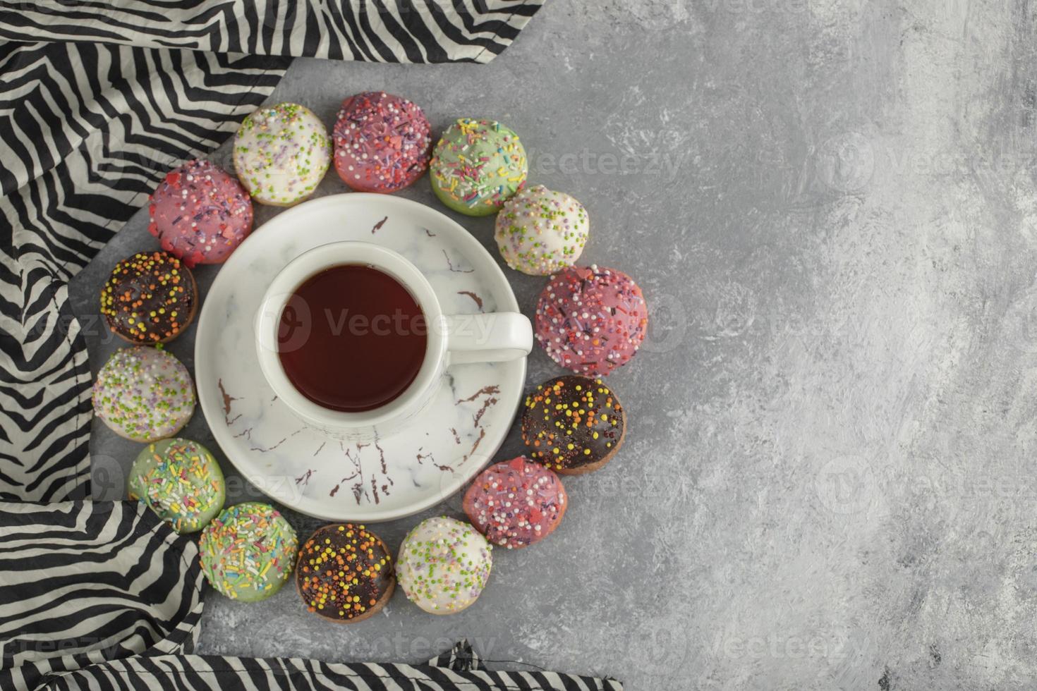 donas dulces de colores con una taza de té foto