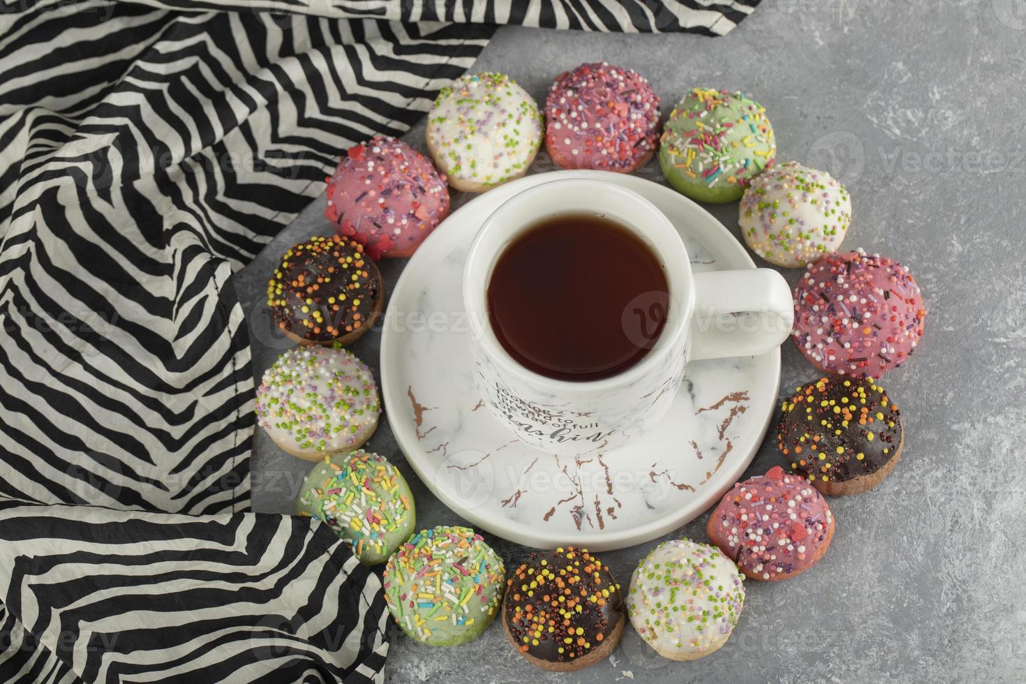 donas dulces de colores con una taza de té foto