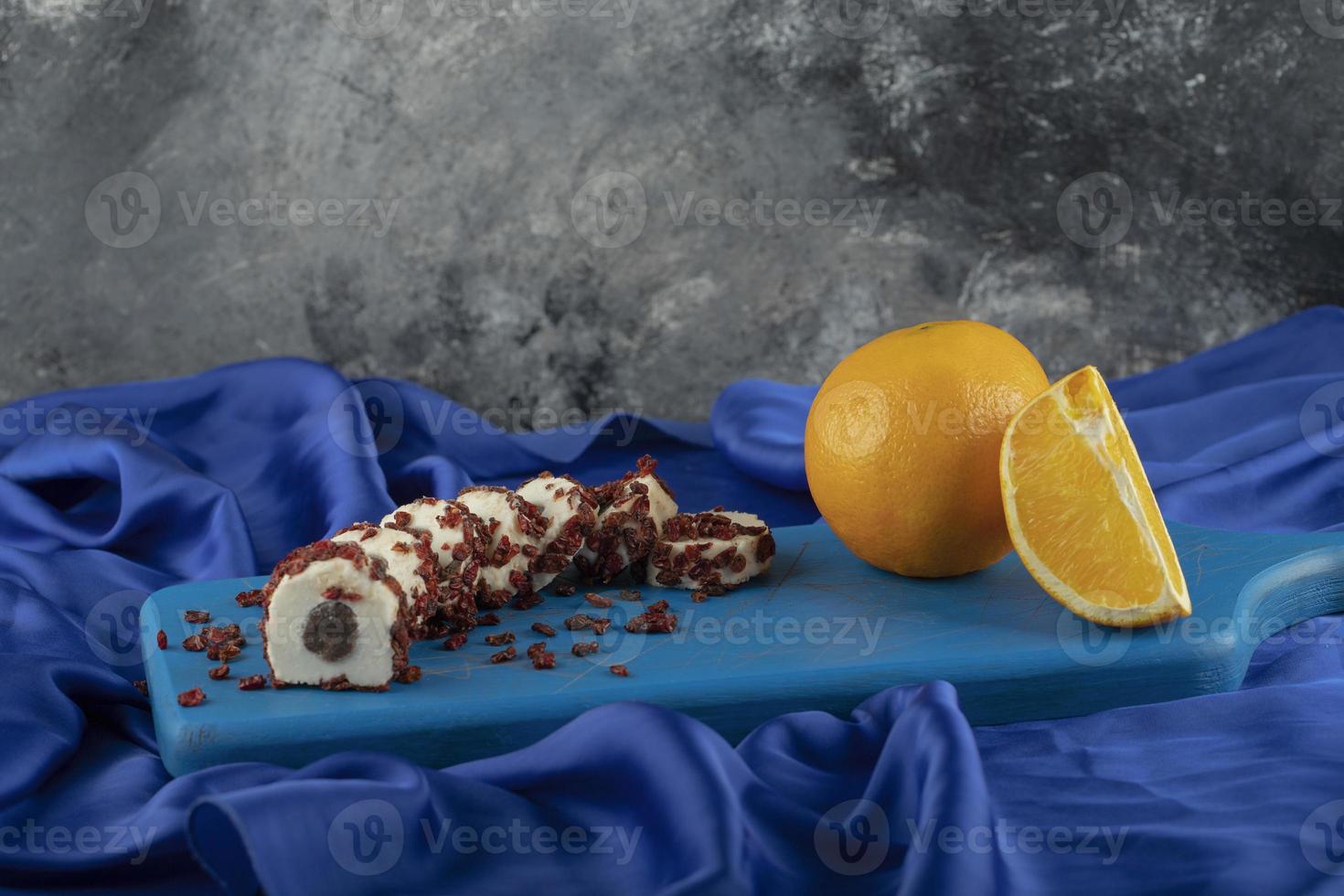 Postre dulce en rodajas con frutos secos sobre una placa azul de madera foto