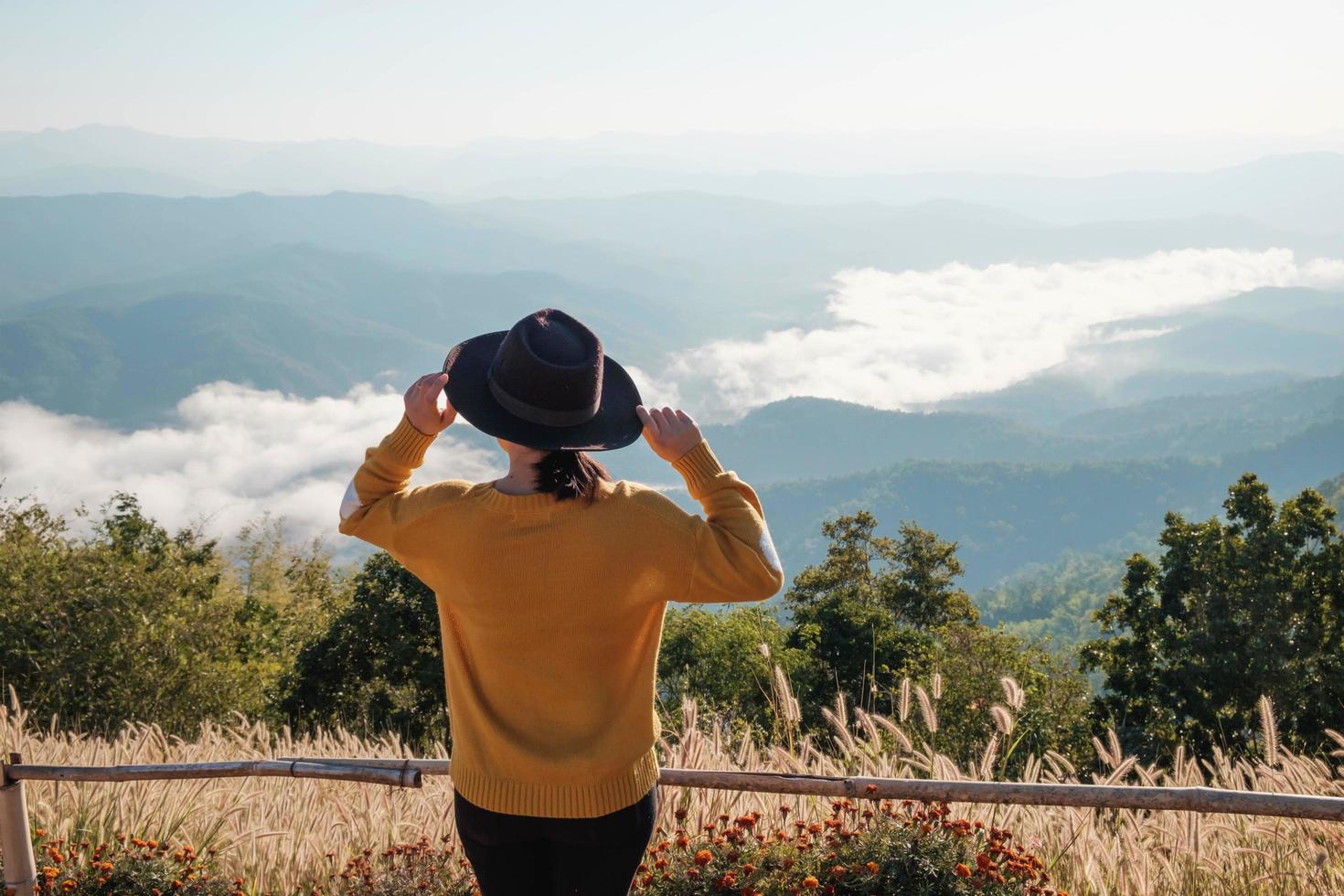 mujer sentada con un sombrero en la cima de una montaña foto