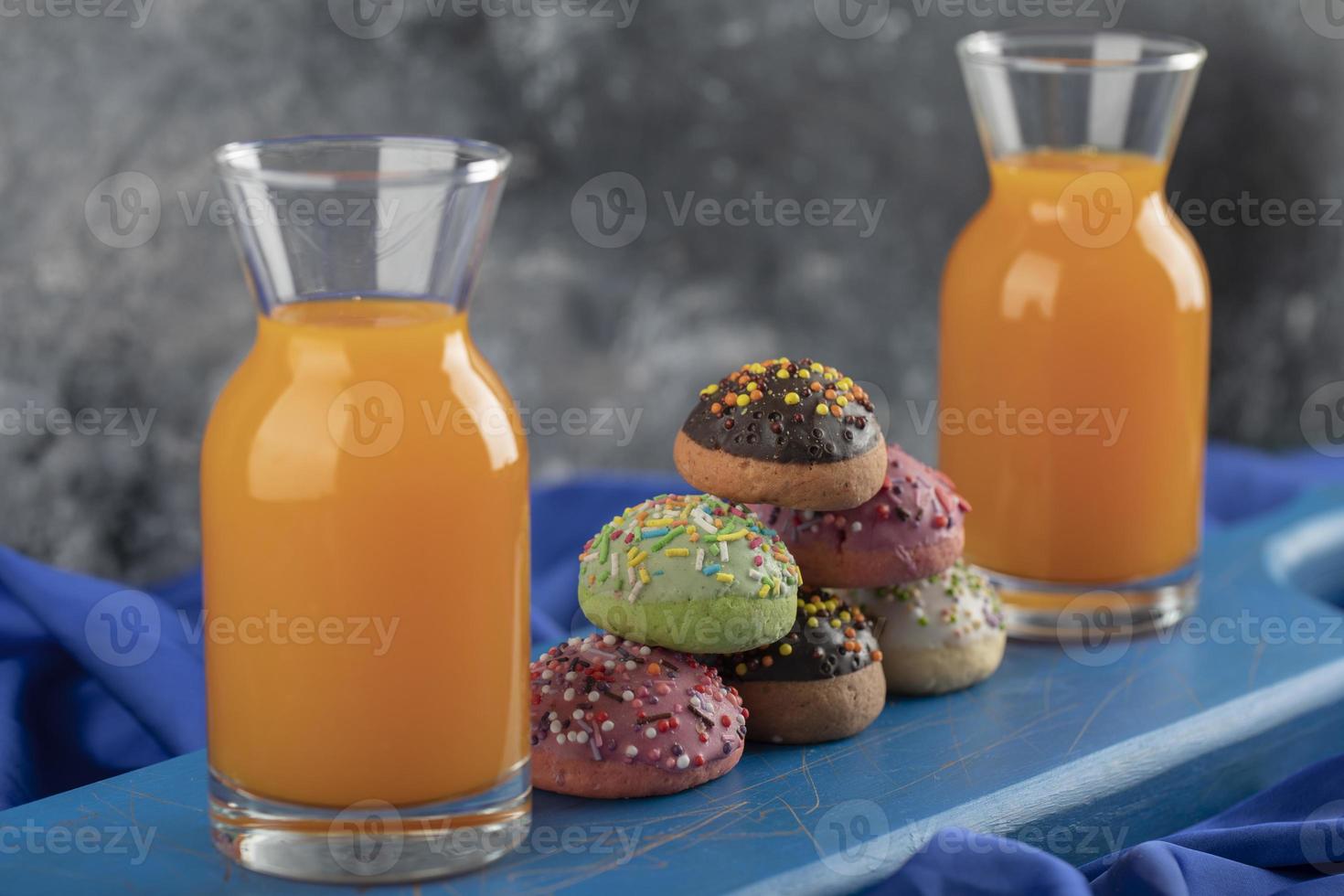 donas dulces de colores con frascos de jugo de vidrio foto